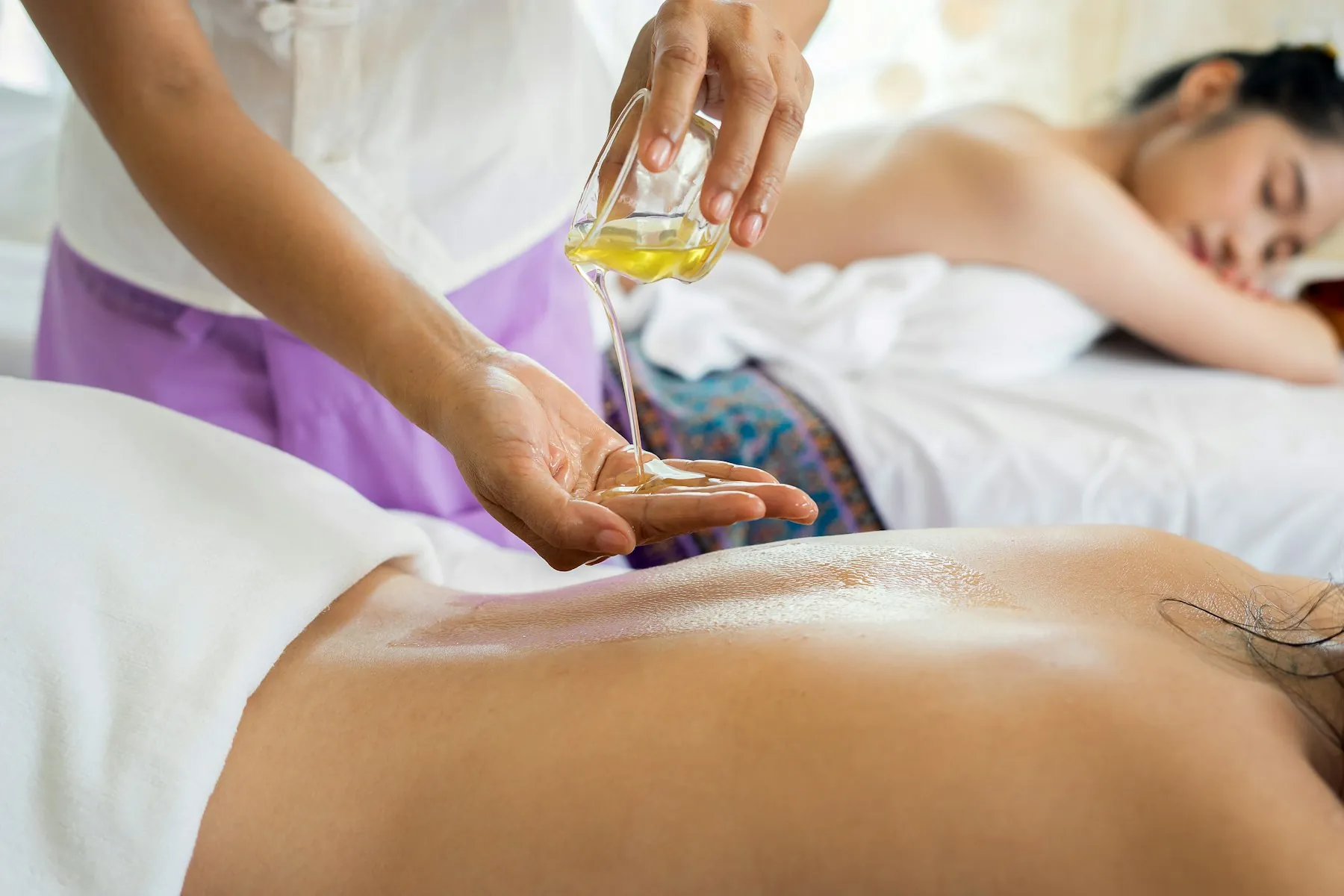Warm massage oil poured over a client's back before long, calming Swedish strokes