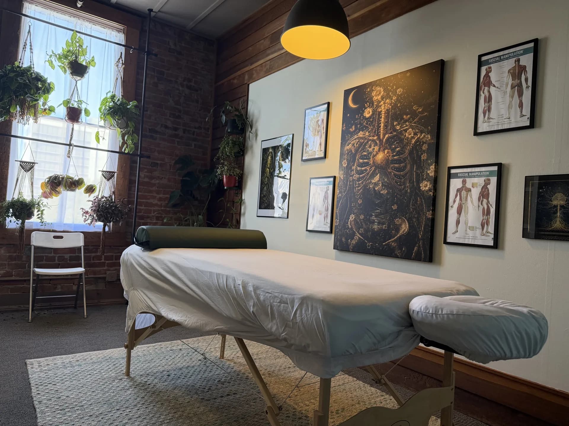 Exposed brick wall and sunlit window with hanging plants in the Eugene studio