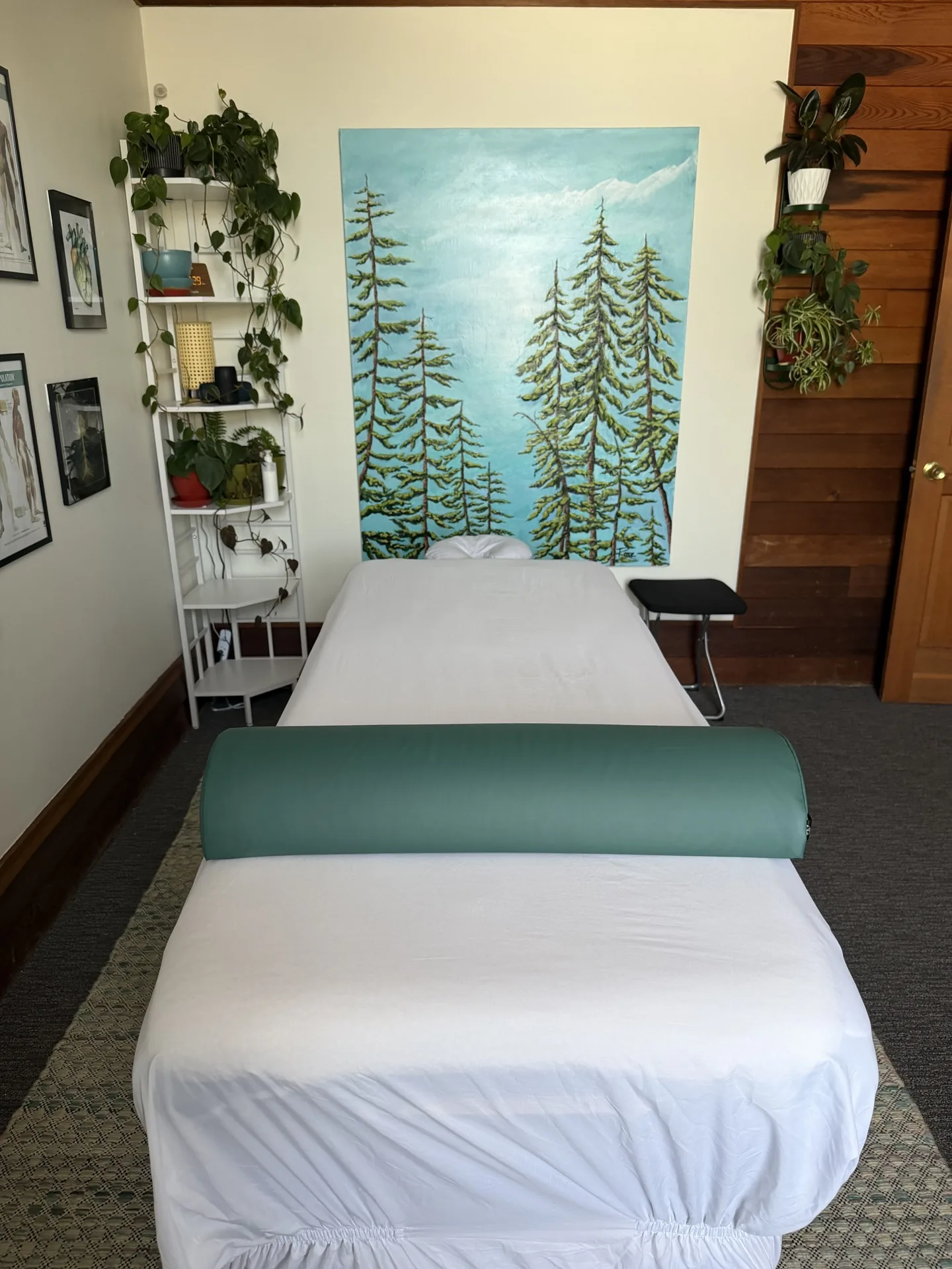 Massage table facing a painted evergreen mural in the Eugene studio