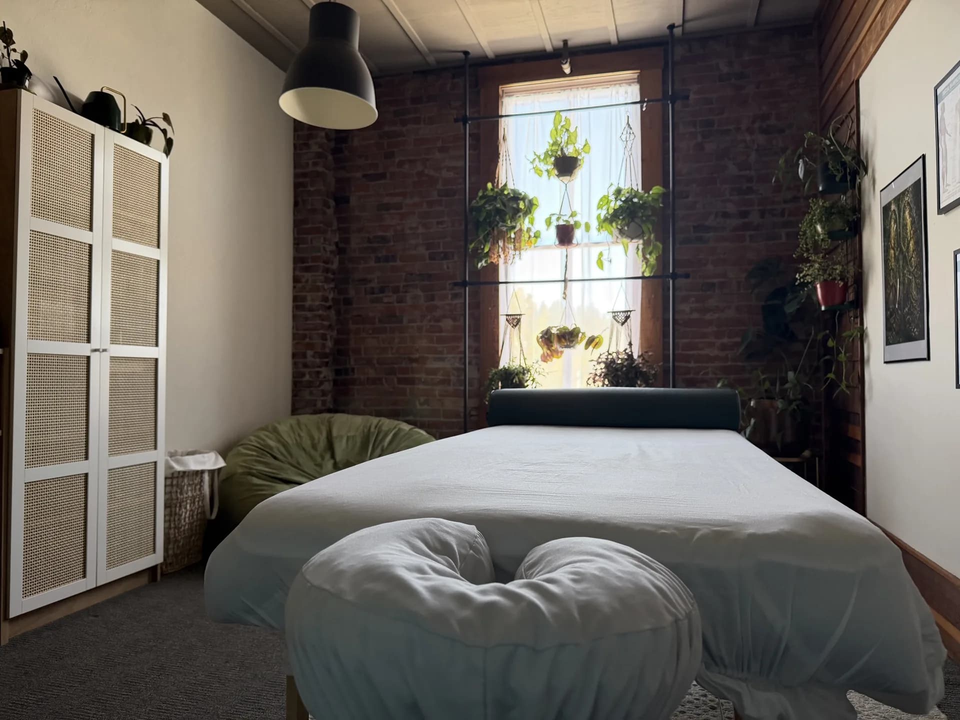View from the head of the massage table toward a window filled with hanging plants