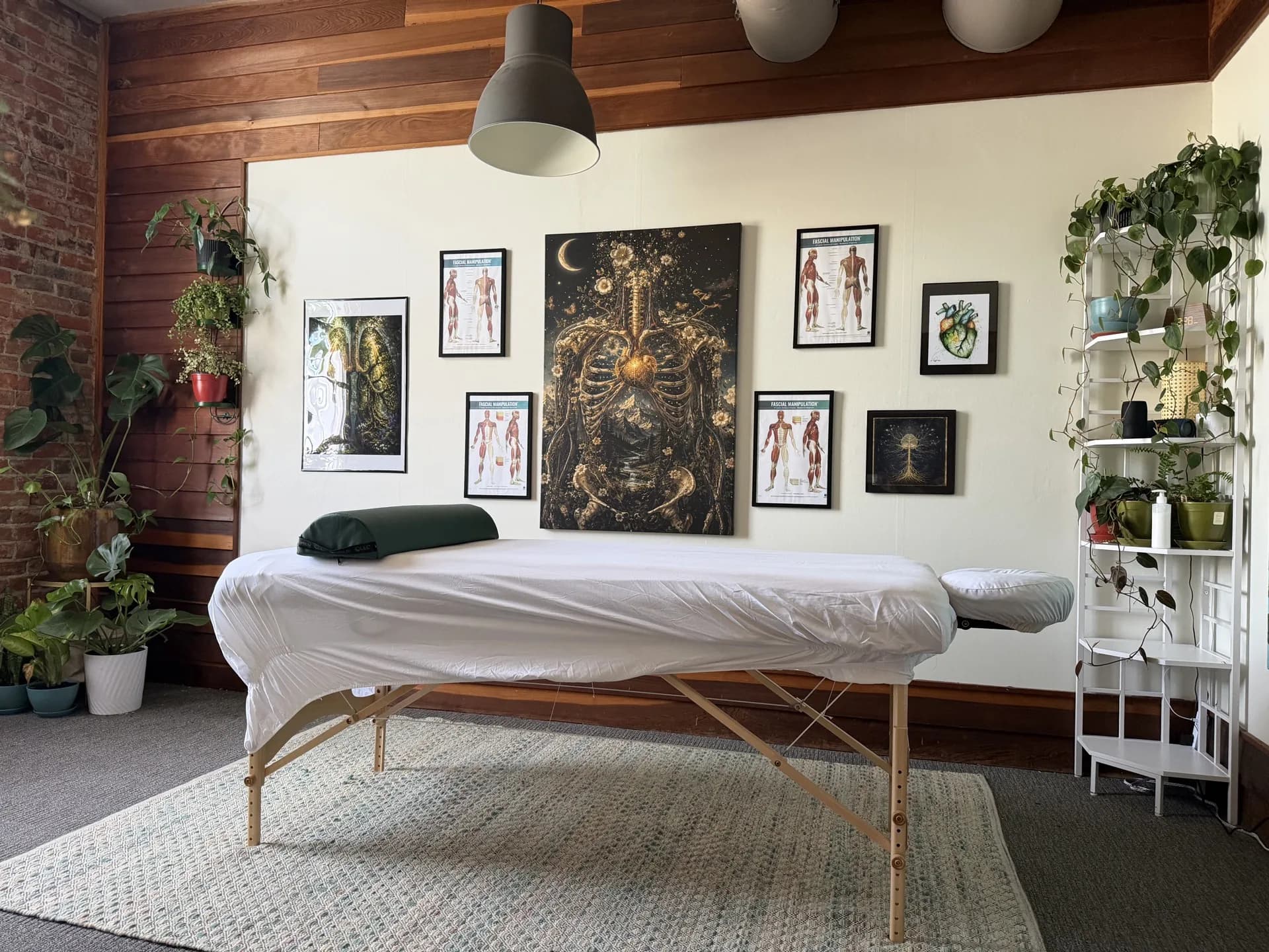 Eugene studio with cedar-paneled walls, brick accent, and a central anatomy canvas